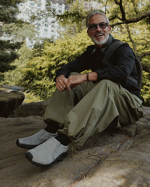 Une personne assise sur un rocher portant des chaussures Merrell Jungle Moc.