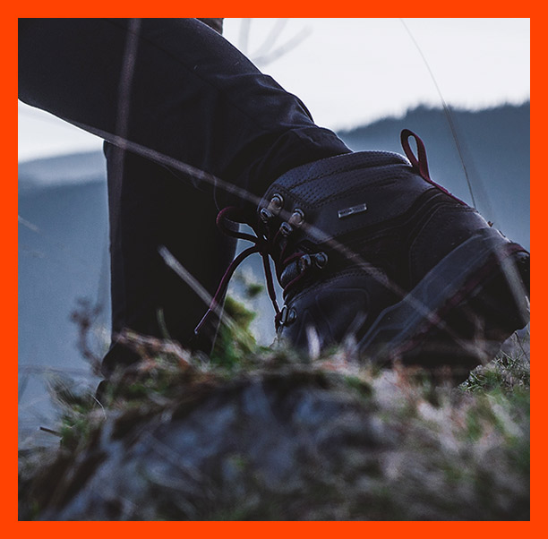 Standing on rocks, taking a photo with a camera.