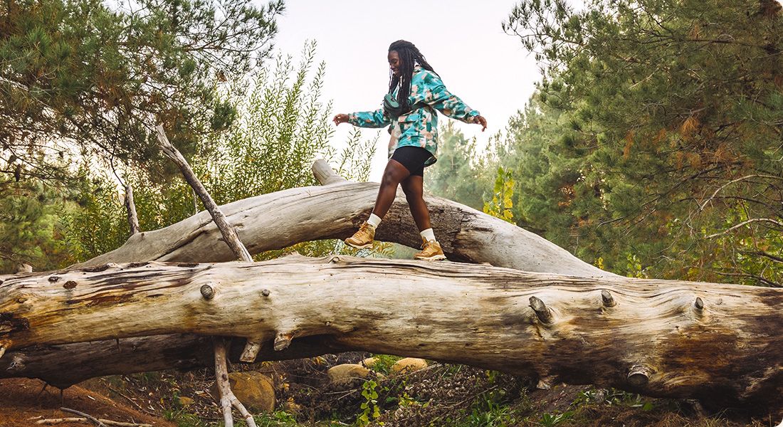 Someone walking on a log wearing Merrell gear.