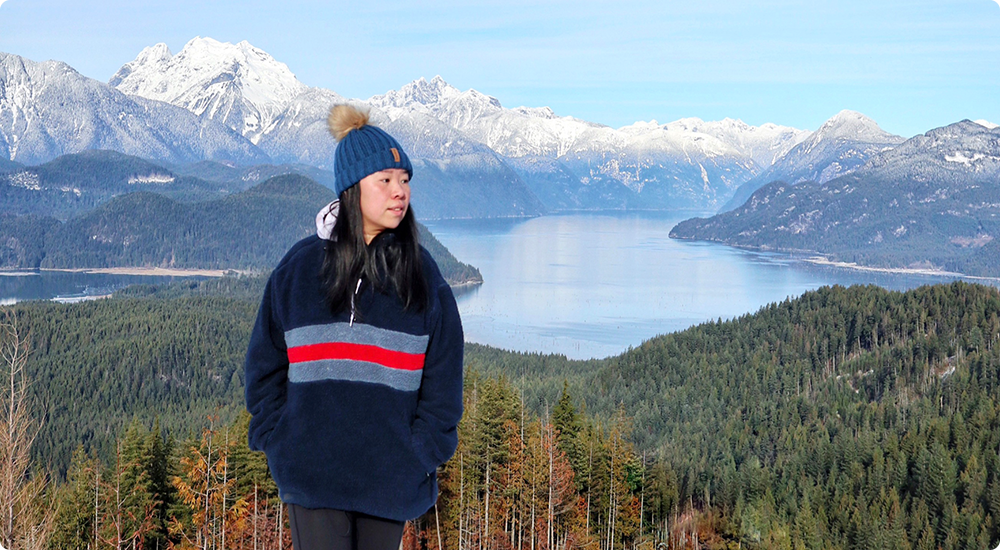 Tilly Tseng debout sur une montagne surplombant un plan d'eau.