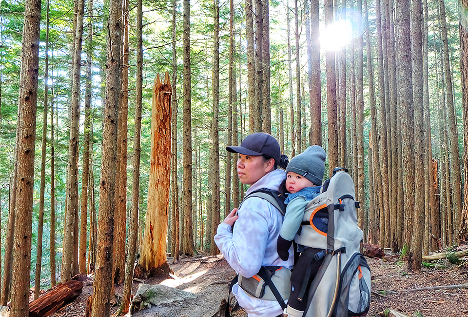 Tilly Tseng porte un bébé dans un sac à dos dans une forêt.