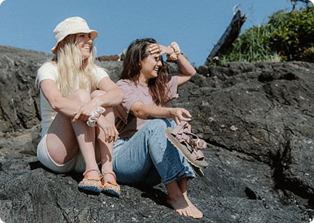 Two people sitting on the rock in Merrell shoes.