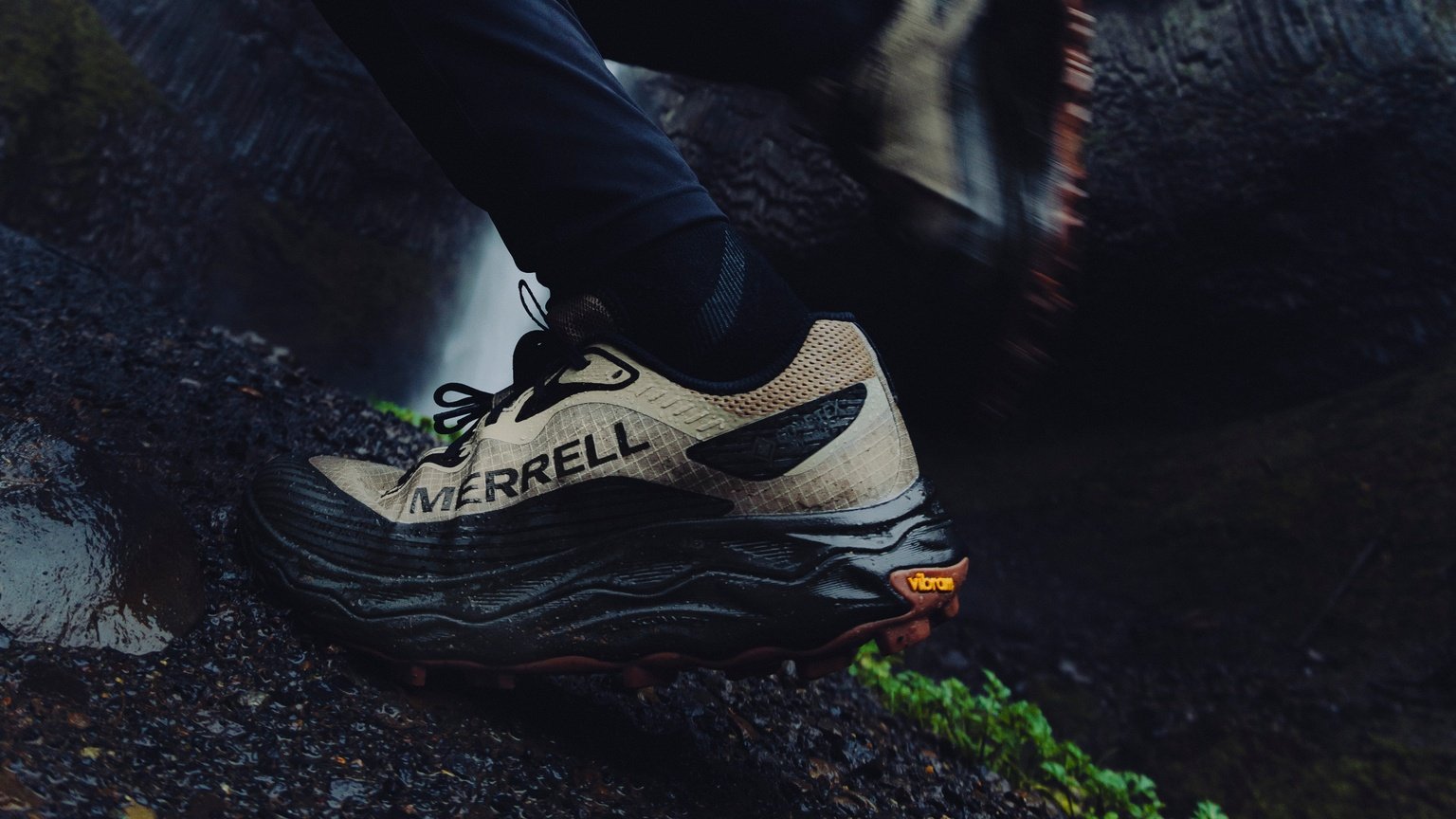Merrell trail shoe stepping through a rain-soaked rocky trail