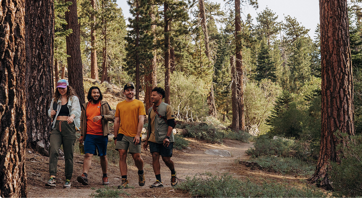 4 people walking in the wood wearing Merrell gear.