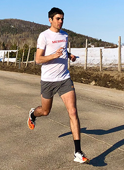 Rémi Leroux running on the road wearing Merrell T-shirt and trail running shoes.
