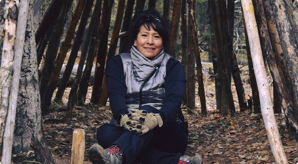 Heather Black sitting in the wood in Merrell gear.