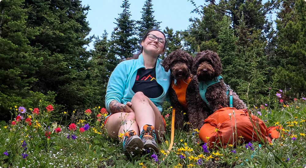 Janine Dersch assise dans un champ avec deux chiens.