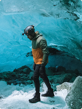 Man in ice cave with winter apparel.