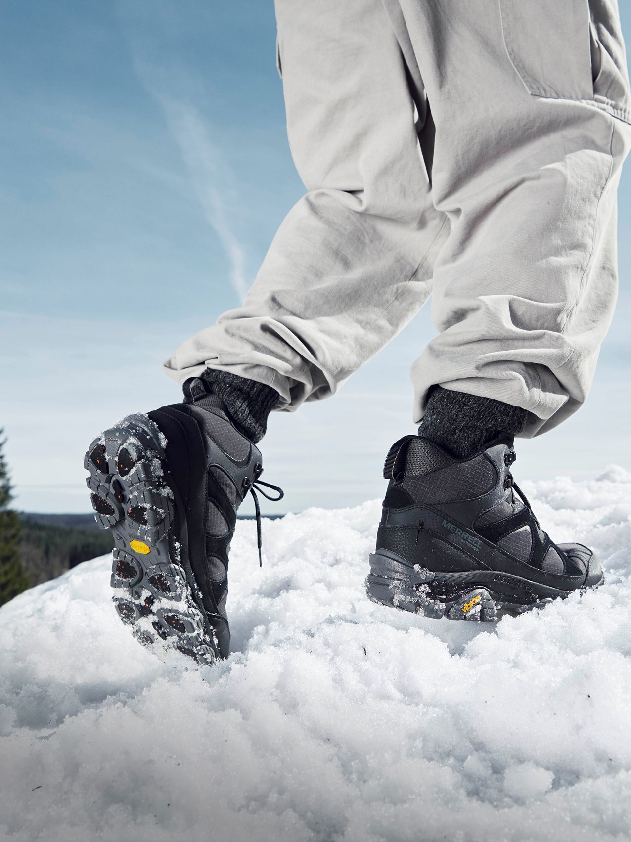Person wearing Merrell boot on a snowy trail.