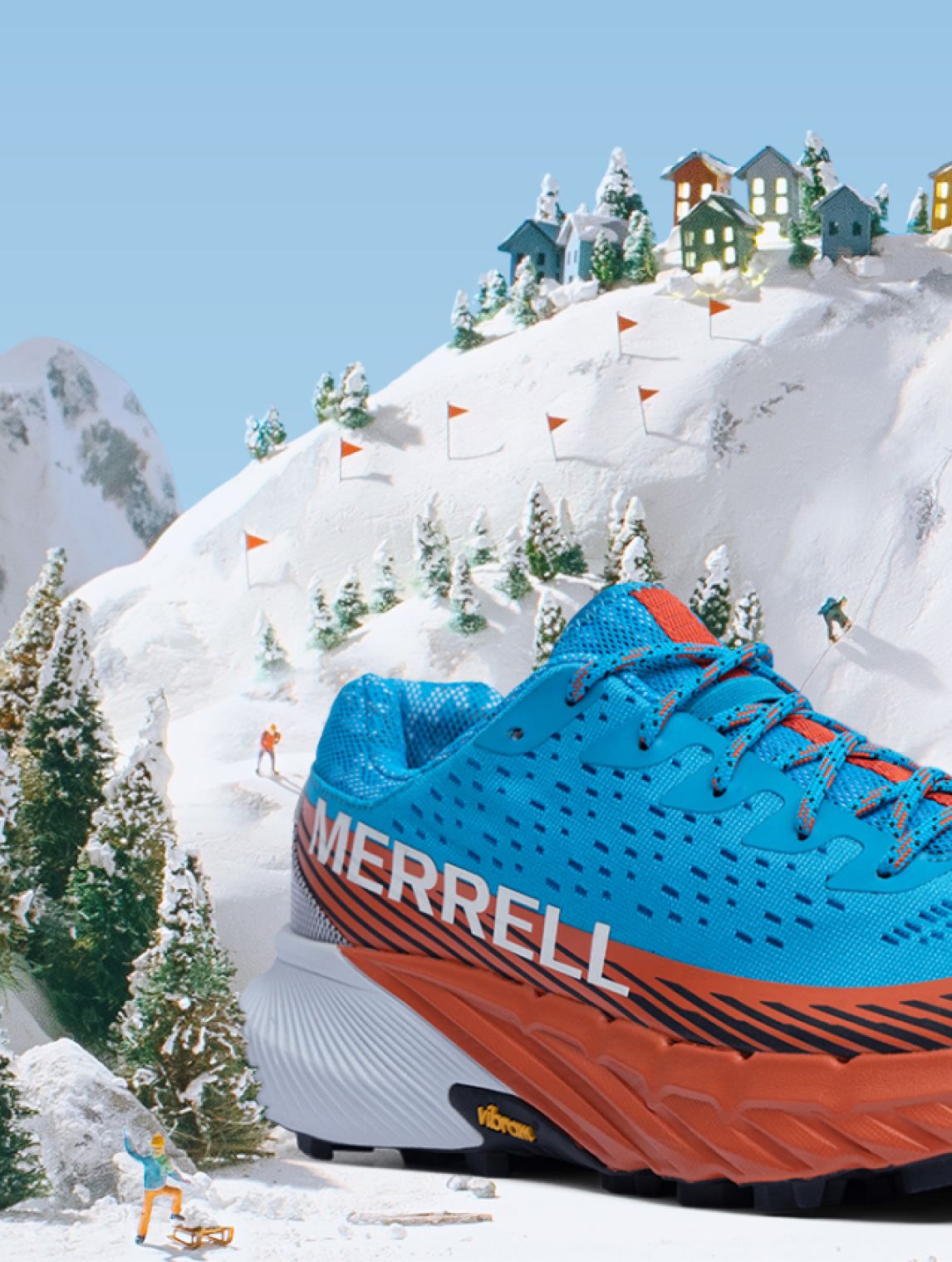 Une chaussure Merrell bleue et orange sur une montagne enneigée.