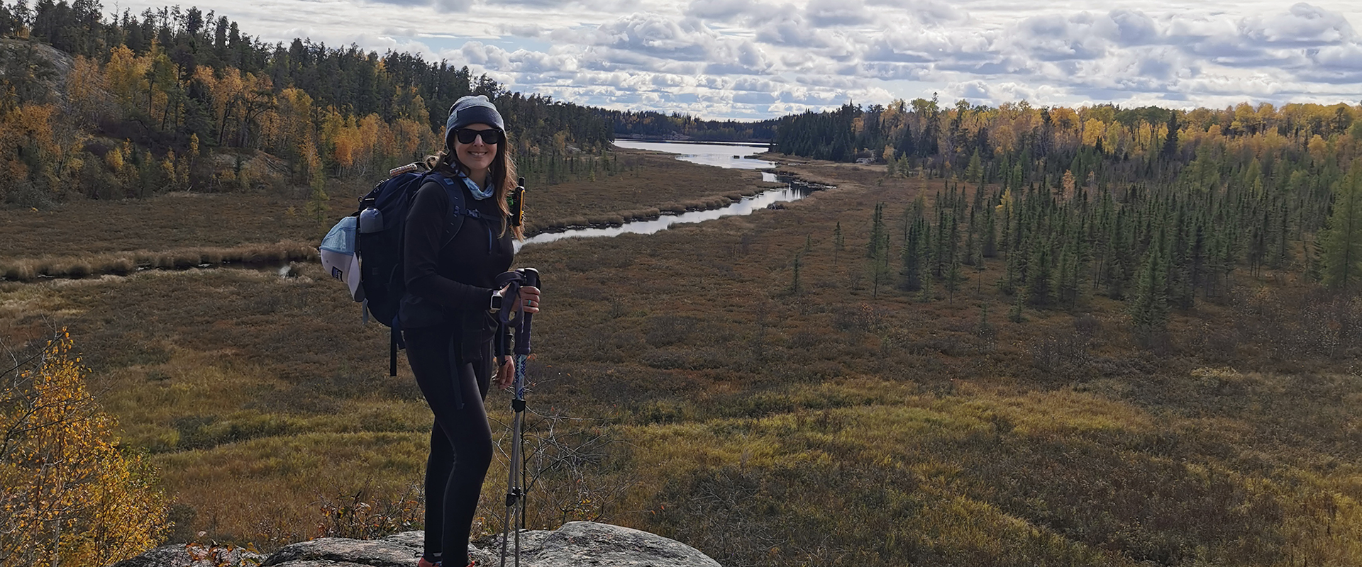 Ashley Moore debout sur un rocher avec une rivière en arrière-plan.