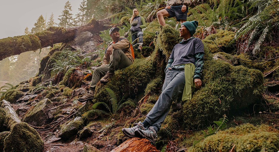 Several people relaxing in the wood wearing Merrell shoes.