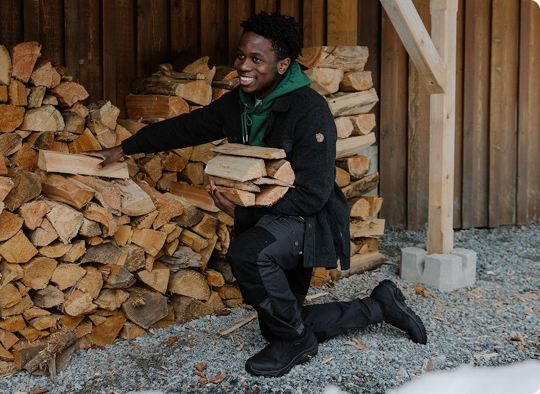 A person holding a pile of wood wearing Merrell gear.