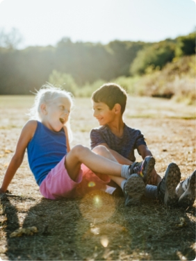 2 kids sitting outside together.