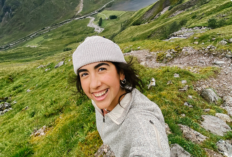 Asalah Youssef taking a selfie on a grassy hill.