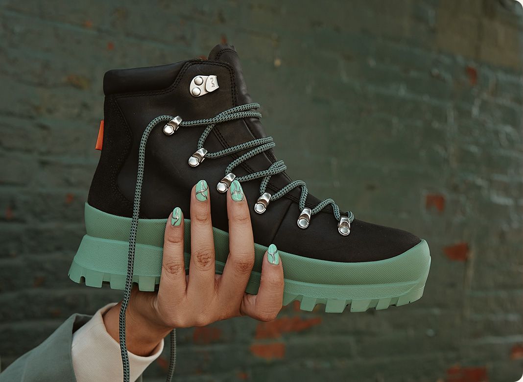 A hand holding a black Merrell boot