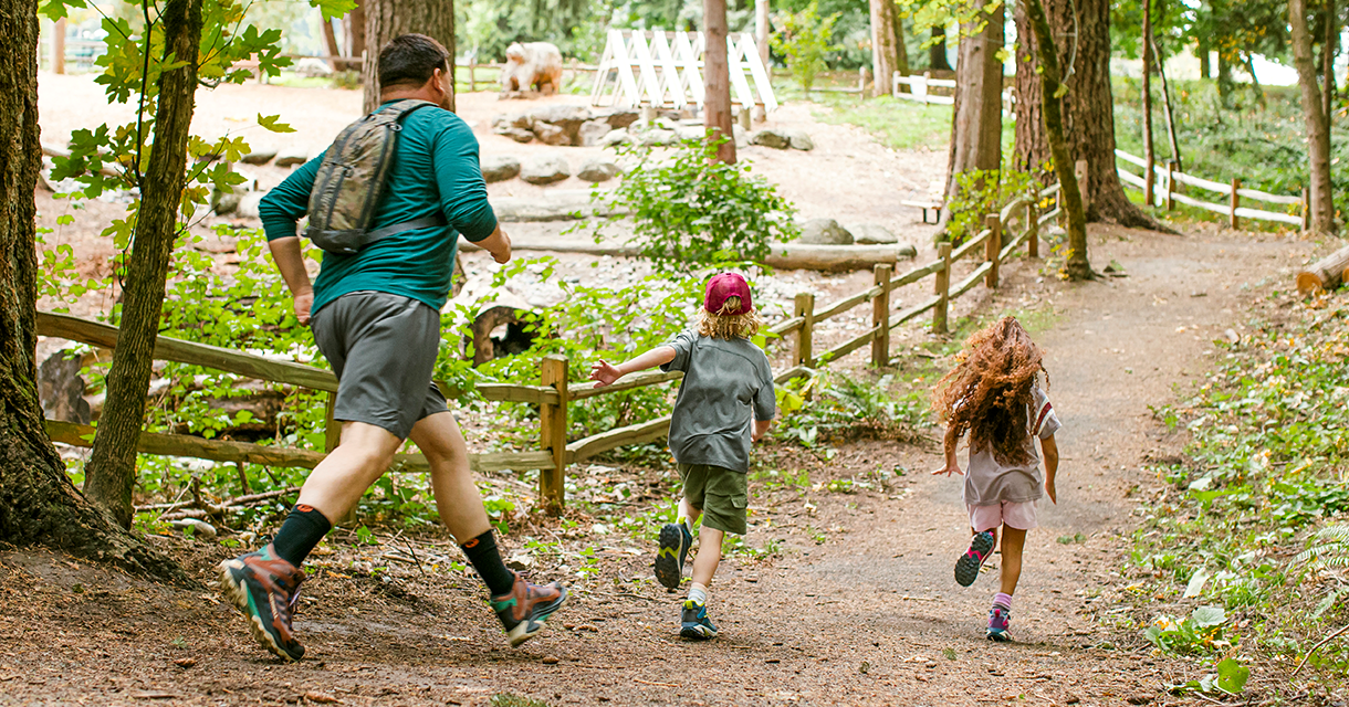 A person and children running on a dirt path wearing Merrell hiking shoes.