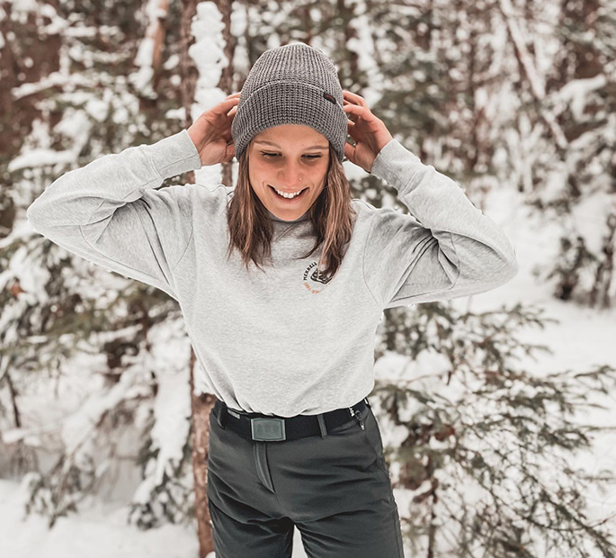 Ariane Lajeunesse portant une casquette Merrell et un pantalon gris dans la neige.