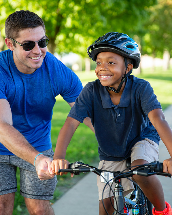 A big brother helping a little brother to ride a bike.