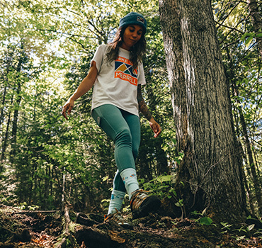 Johany Sergerie standing on a log in the woods.