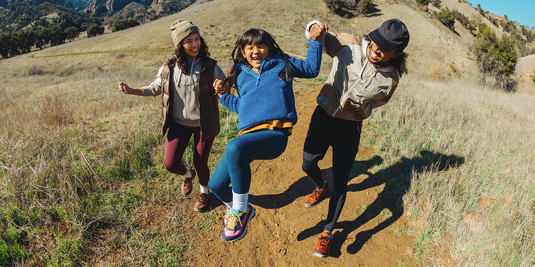 Three people smiling somewhere outside wearing Merrell gears.
