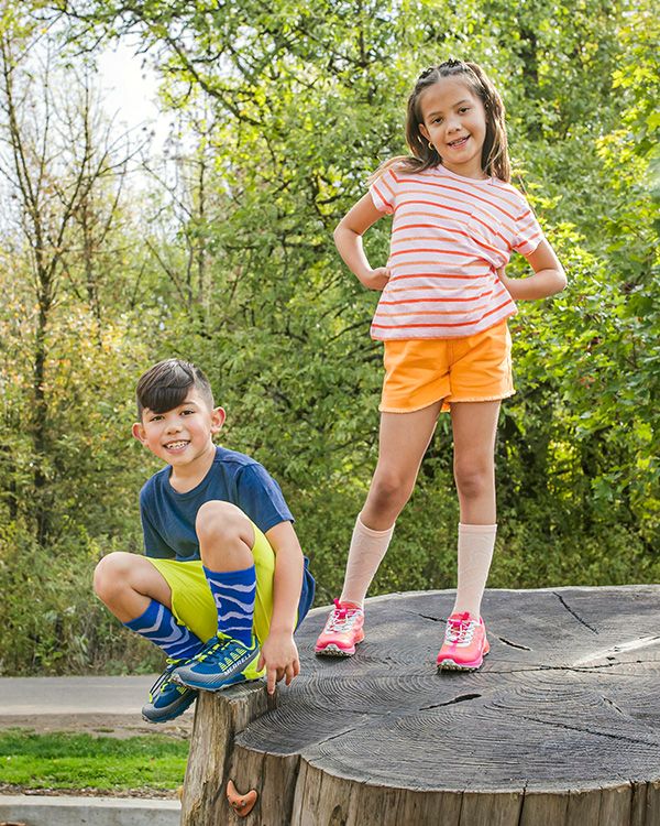 Deux enfants posant pour une photo en portant des chaussures Merrell.