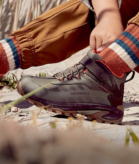 Enfant en train d'enfiler ses chaussures.