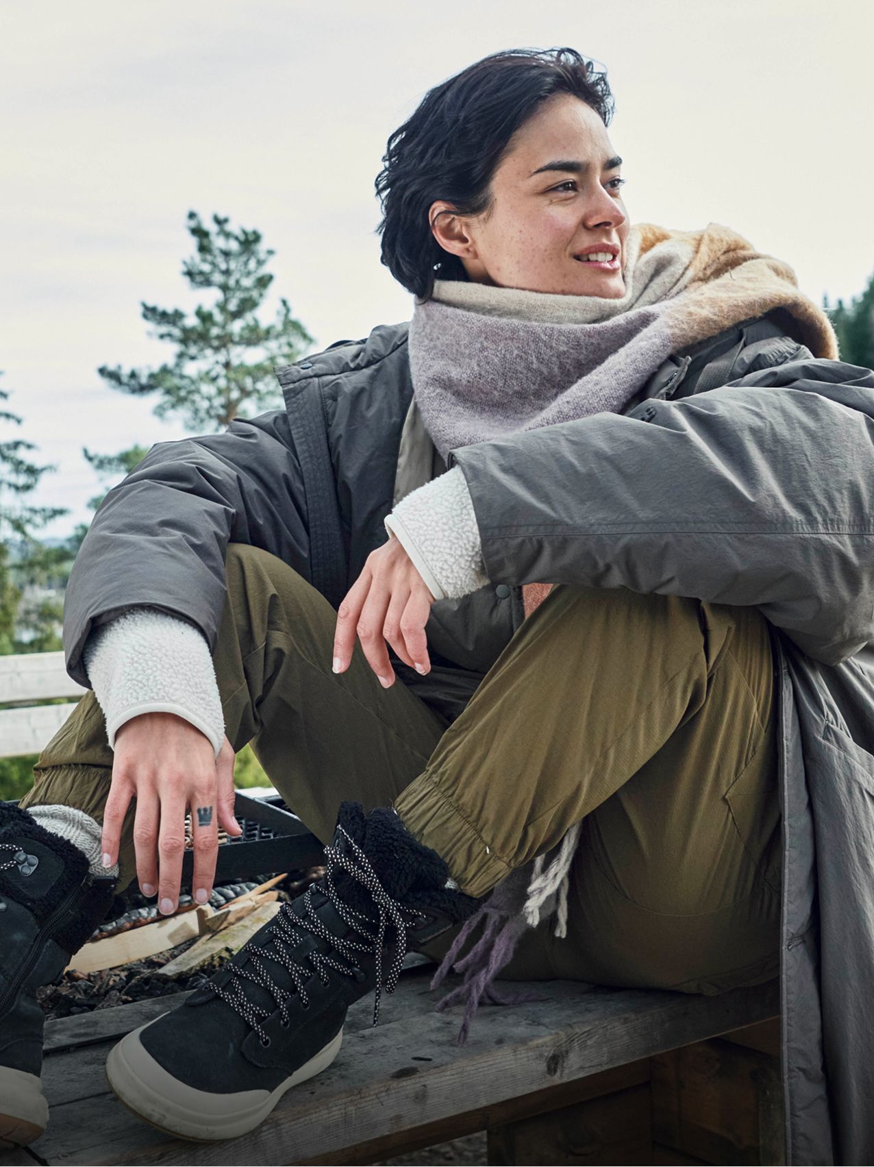 Young girl sitting on a rock, smiling, wearing colorful Merrell shoes.
