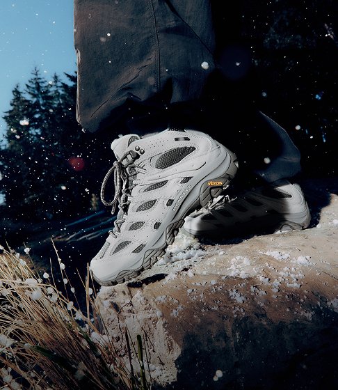 Light grey Merrell waterproof hiking boots on a snow-covered rock.