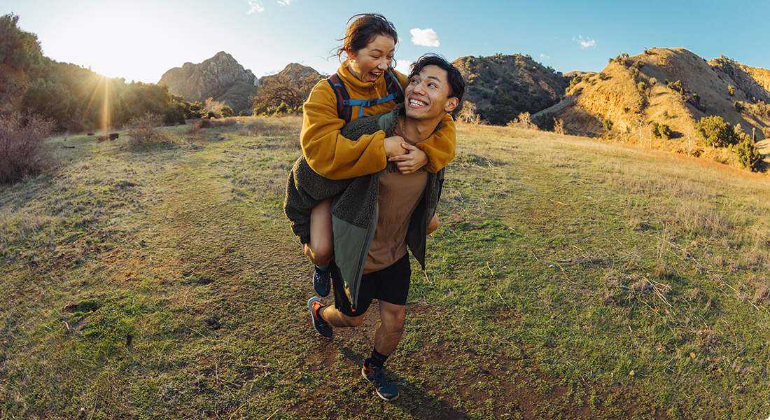 Two happy people laughing somewhere outside wearing Merrell gears.