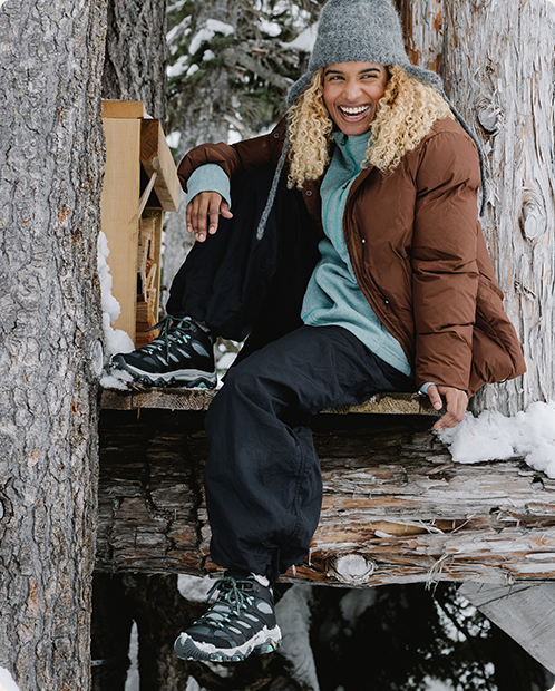 A woman sitting on a tree wearing a pair of Moab boots.