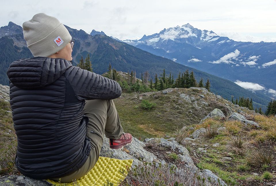 Michelle Agon assise sur un rocher regardant les montagnes.