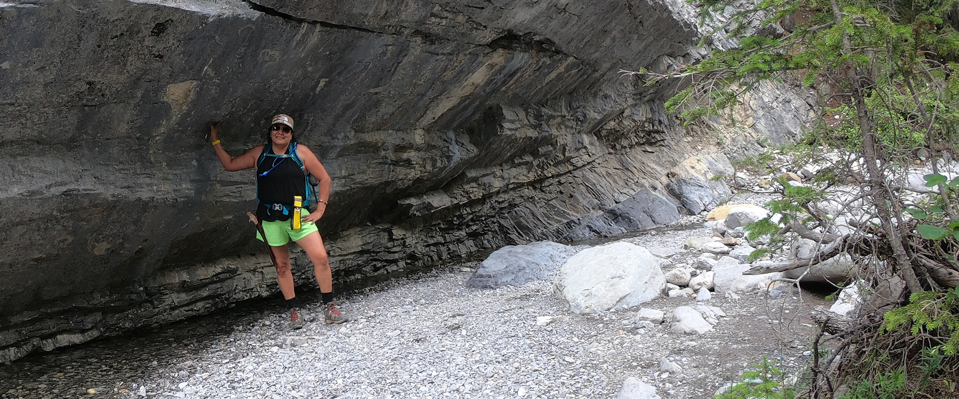 Heather Black beside the rock wearing Merrell gear.