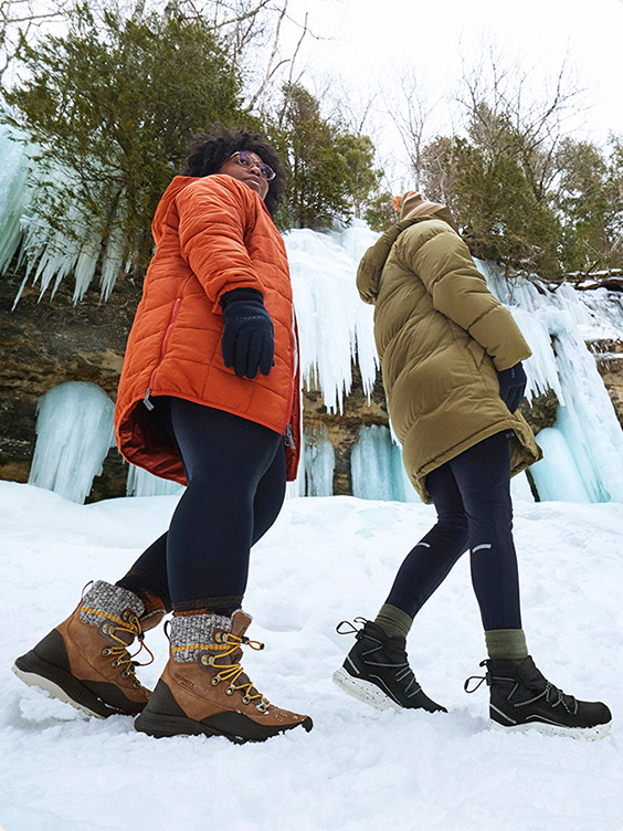 Two people walking in the snow forest in Merrell boots.