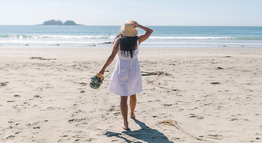 Someone in a white dress on the beach wearing Merrell gears.