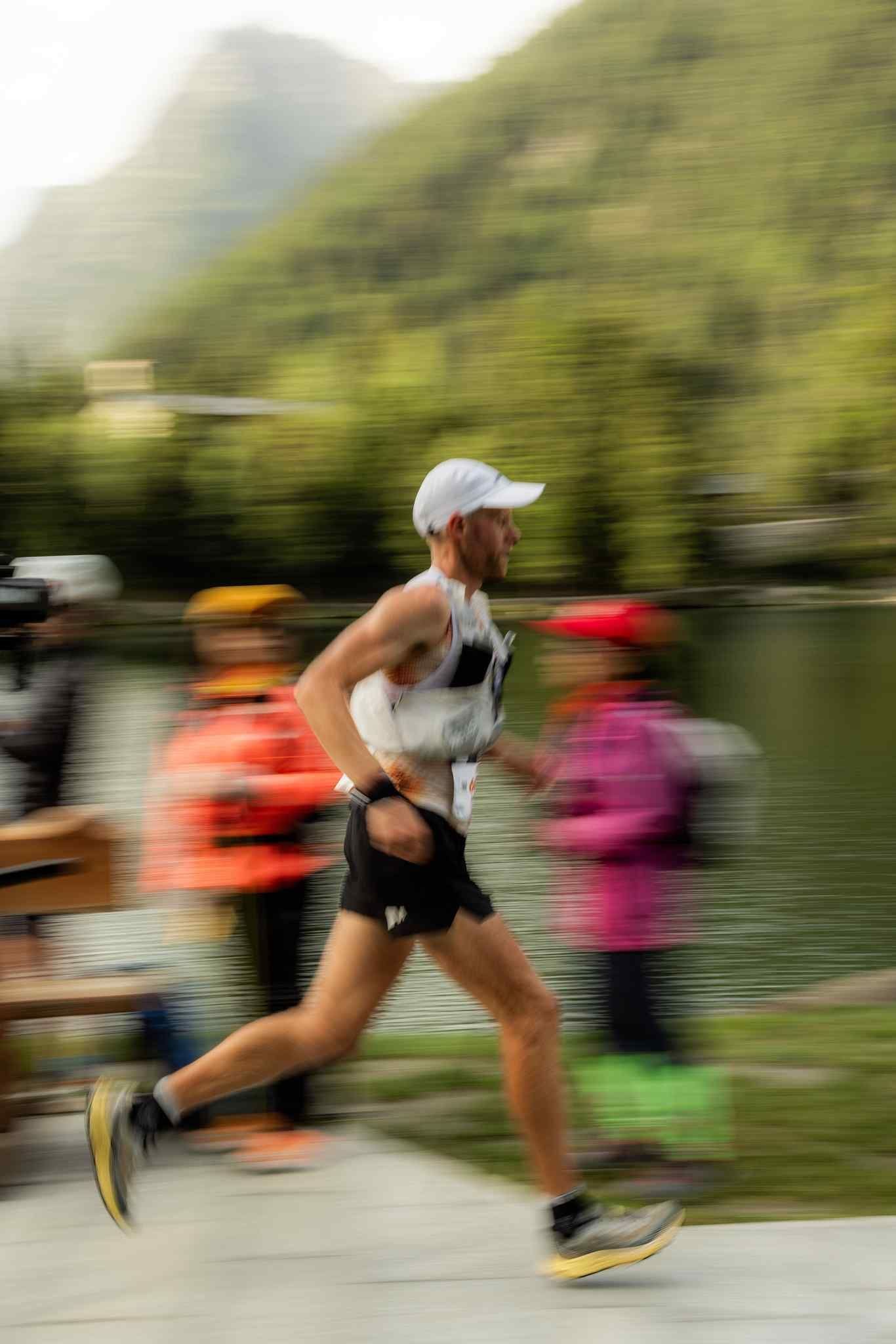 A trail runner racing past a lake.