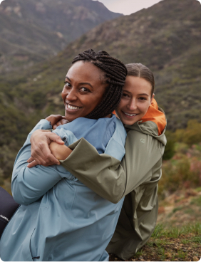 Two women hugging on a mountainside