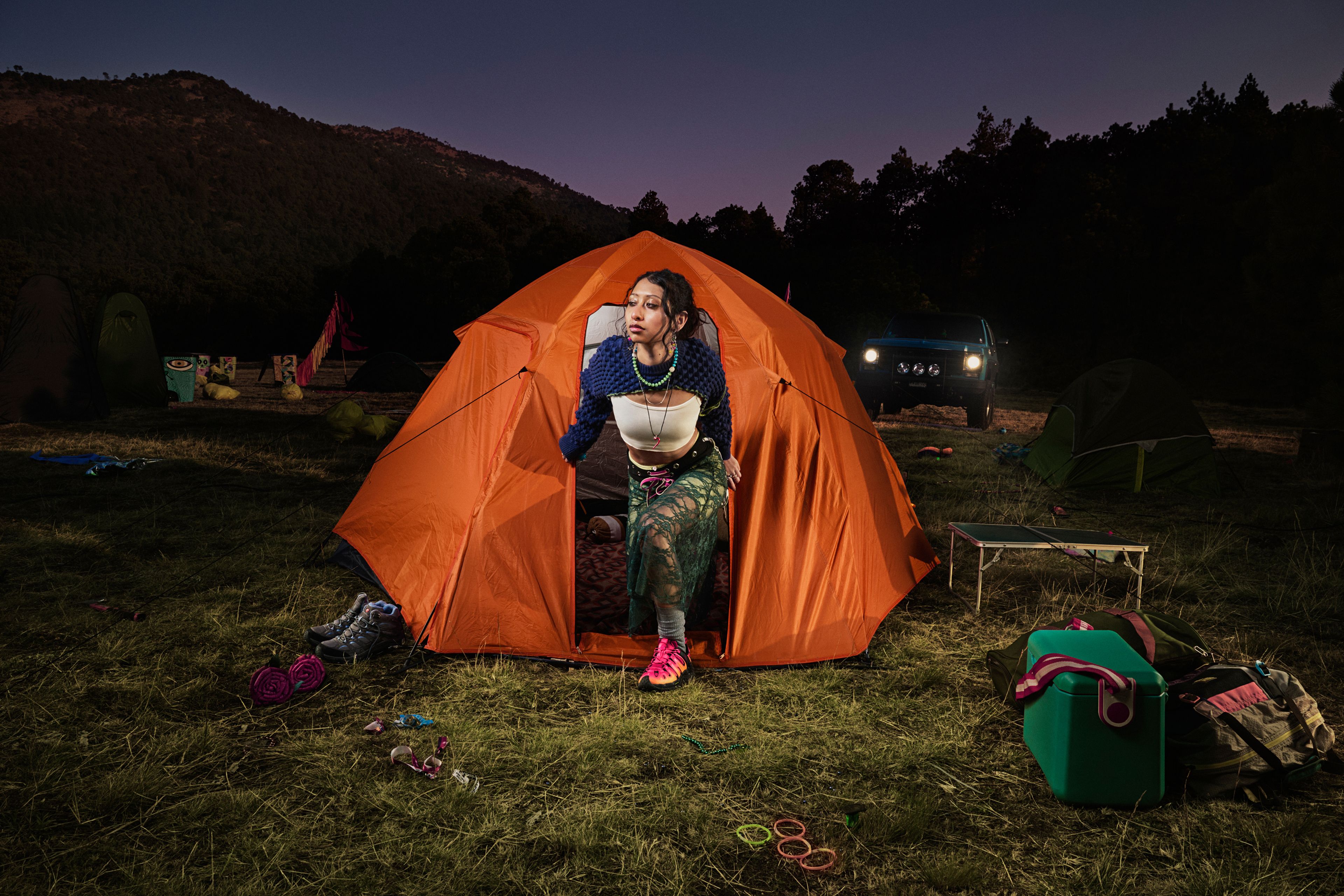Person emerging from orange tent in outdoor camping setting wearing Merrell gear