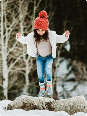 Person sitting on a tree stump in a forest looking cozy.