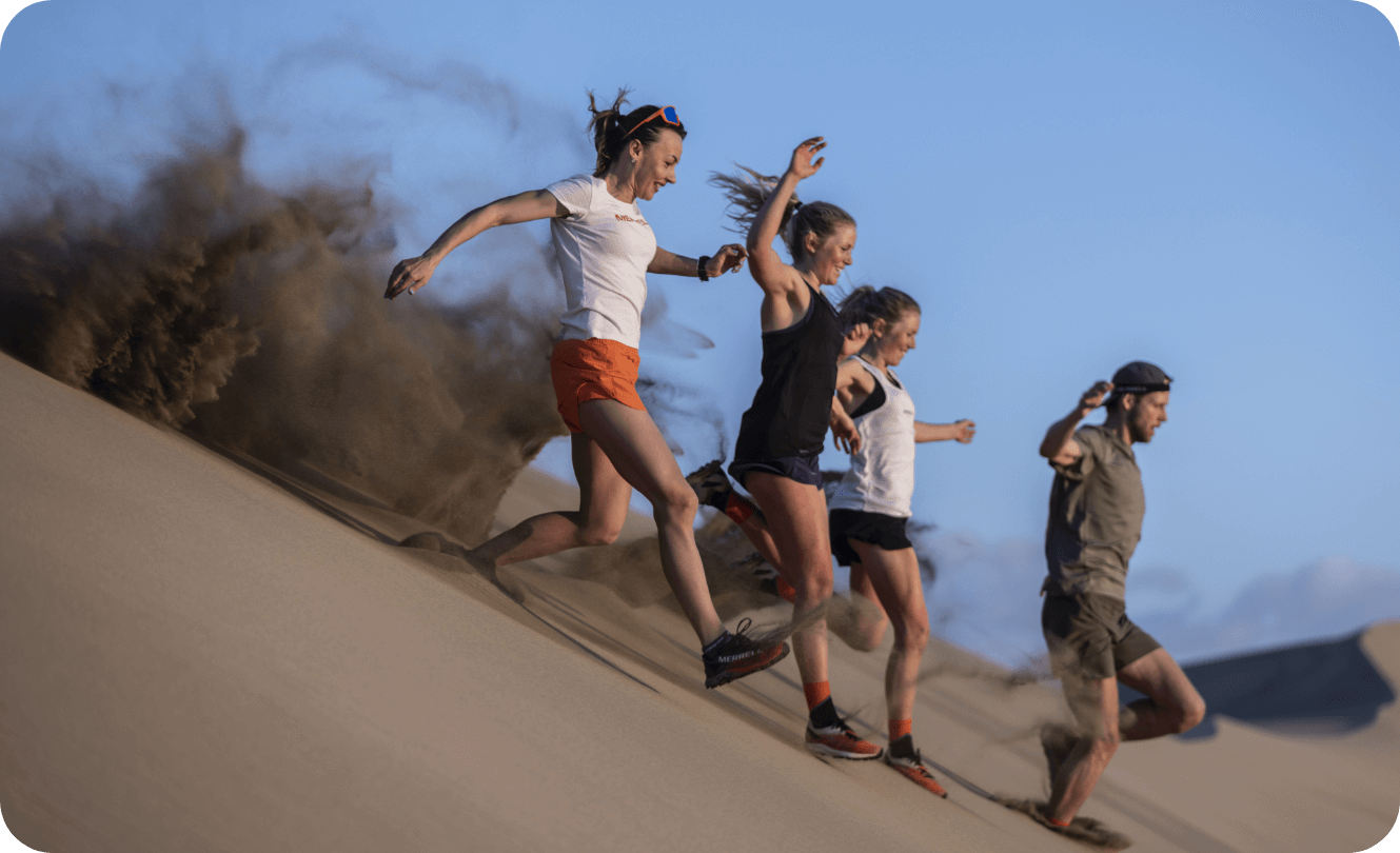 People running down sandy hill in Merrell gear.