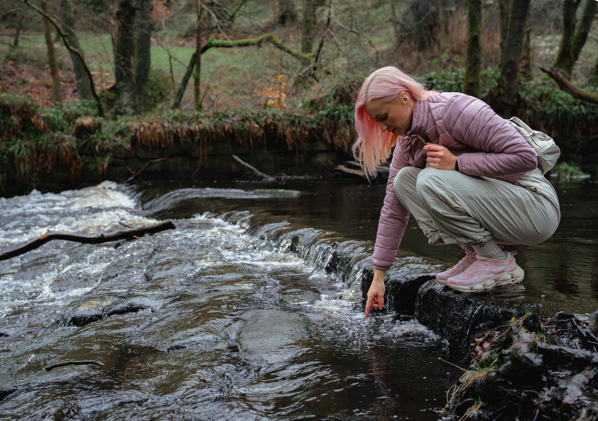 Woman crouching by a stream in the outdoors