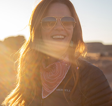 Nicole Brown is smiling while the dessert sun sets behind her.