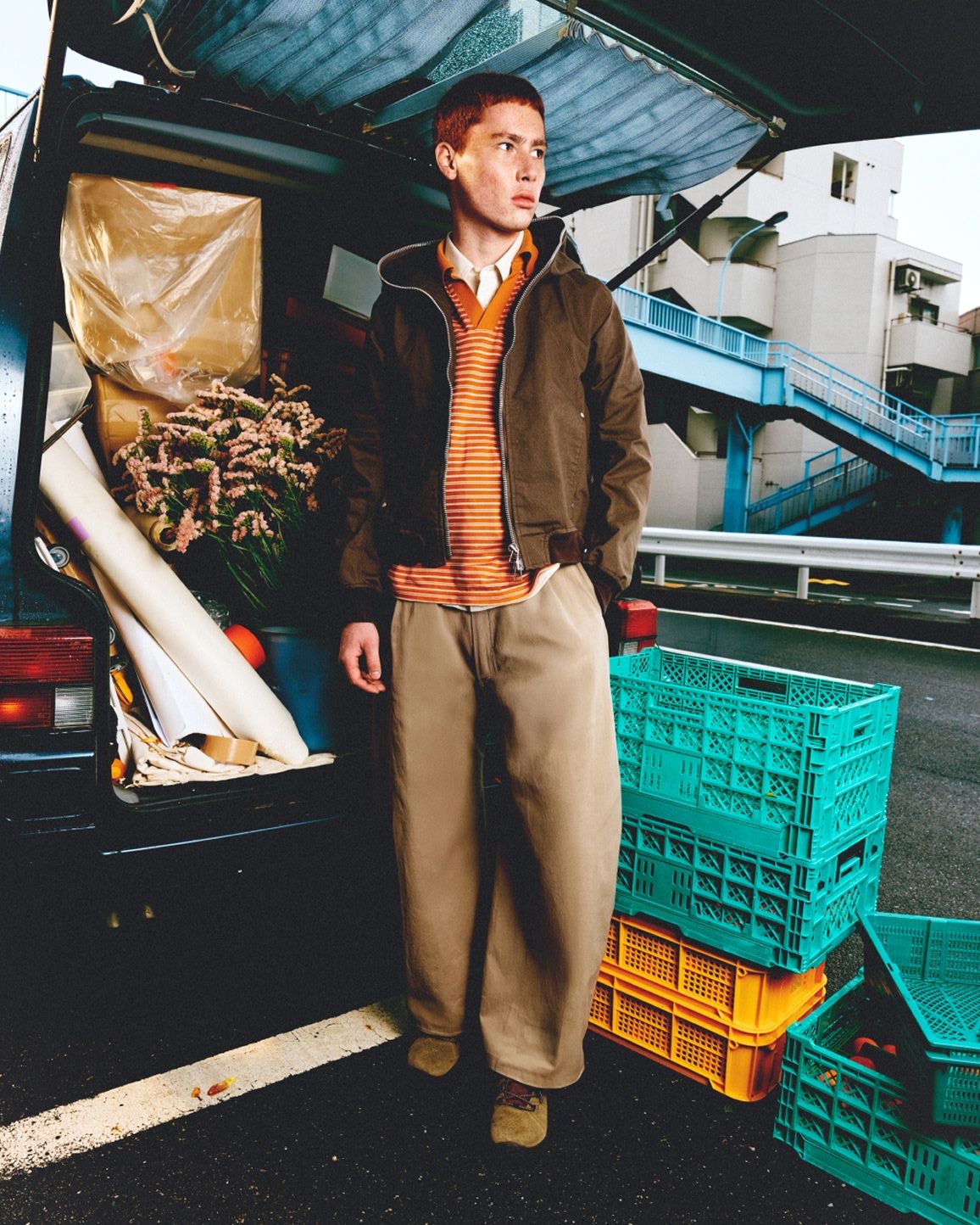 A person wearing Merrell barefoot shoes standing behind a vehicle.