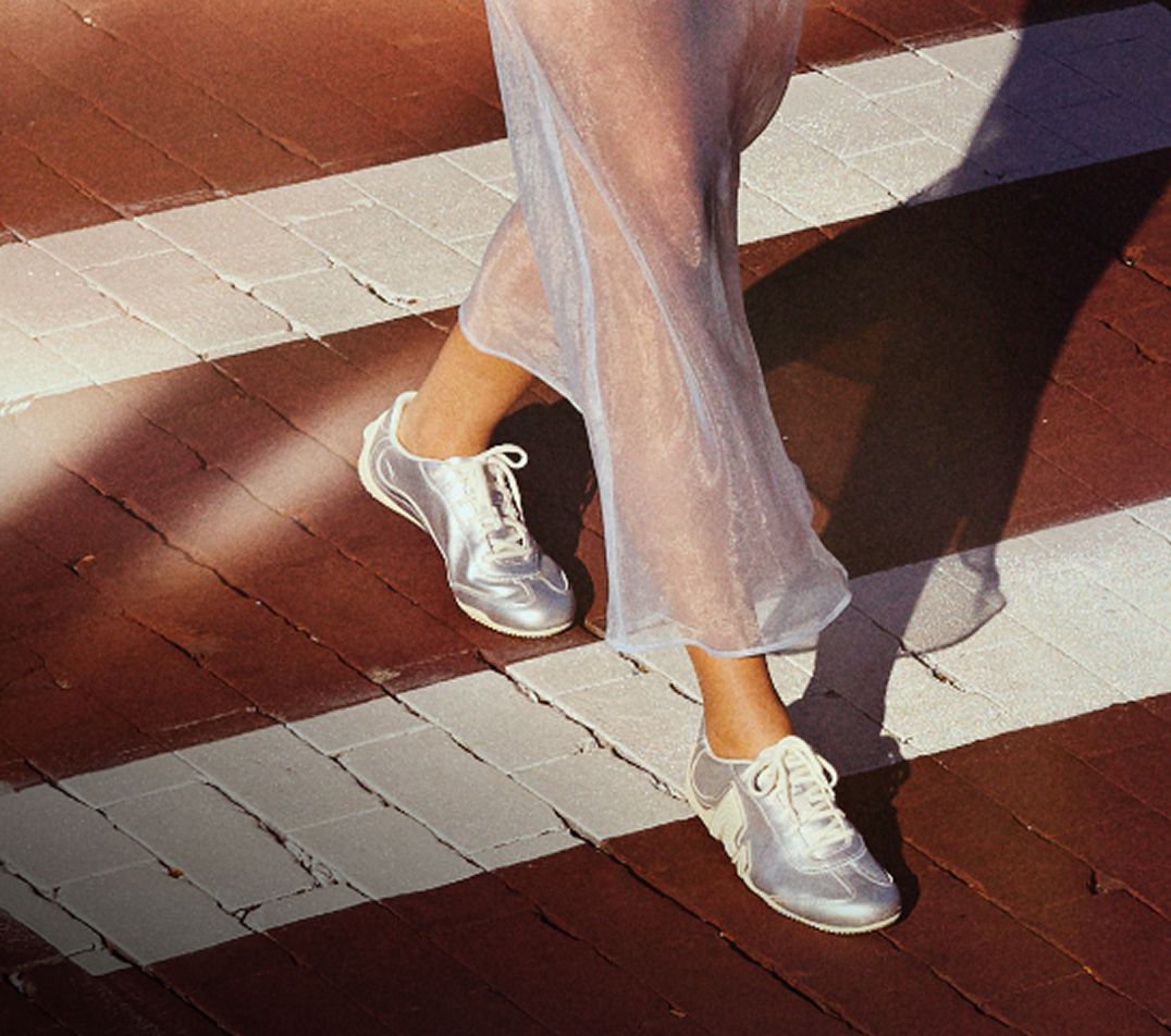 Close up of a woman wearing Merrell shoes while walking on a cross walk.