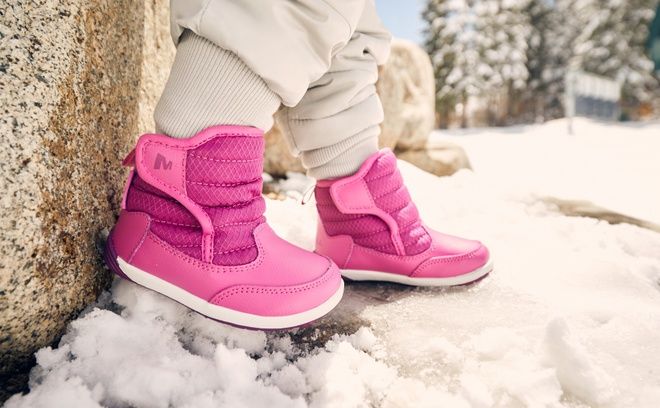 Pink kids’ winter boots in the snow.