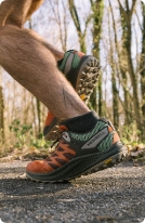 Person's feet in Merrell shoes, running outside.