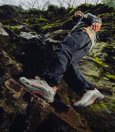 Hiker climbing a mossy rock face.