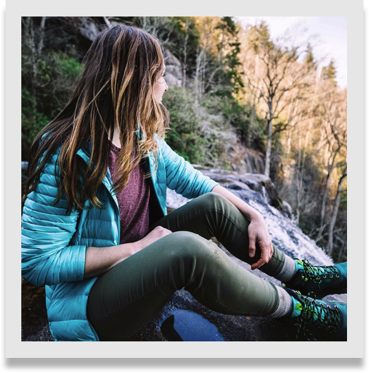 Female sitting on the mountainside, looking out over the natural splendor.