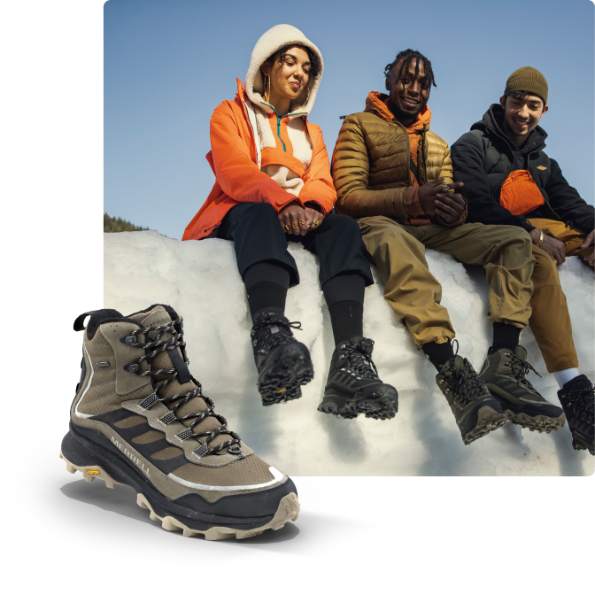 Three people wearing boots while sitting on a block of ice.