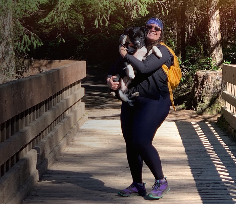 Woman holding her dog on a bridge.